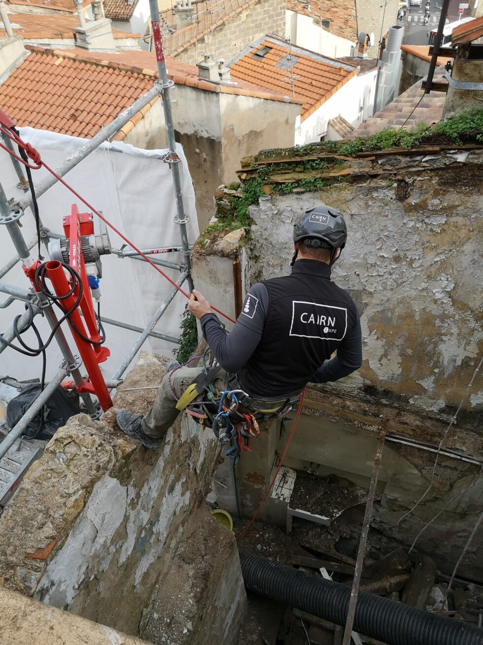 Cordiste CAIRN Expe équipé d’un harnais et d’un casque dans un chantier de rénovation en hauteur.