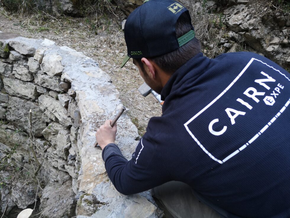 Intervenant CAIRN Expe travaillant sur la maçonnerie du parapet d’un pont en pierre.