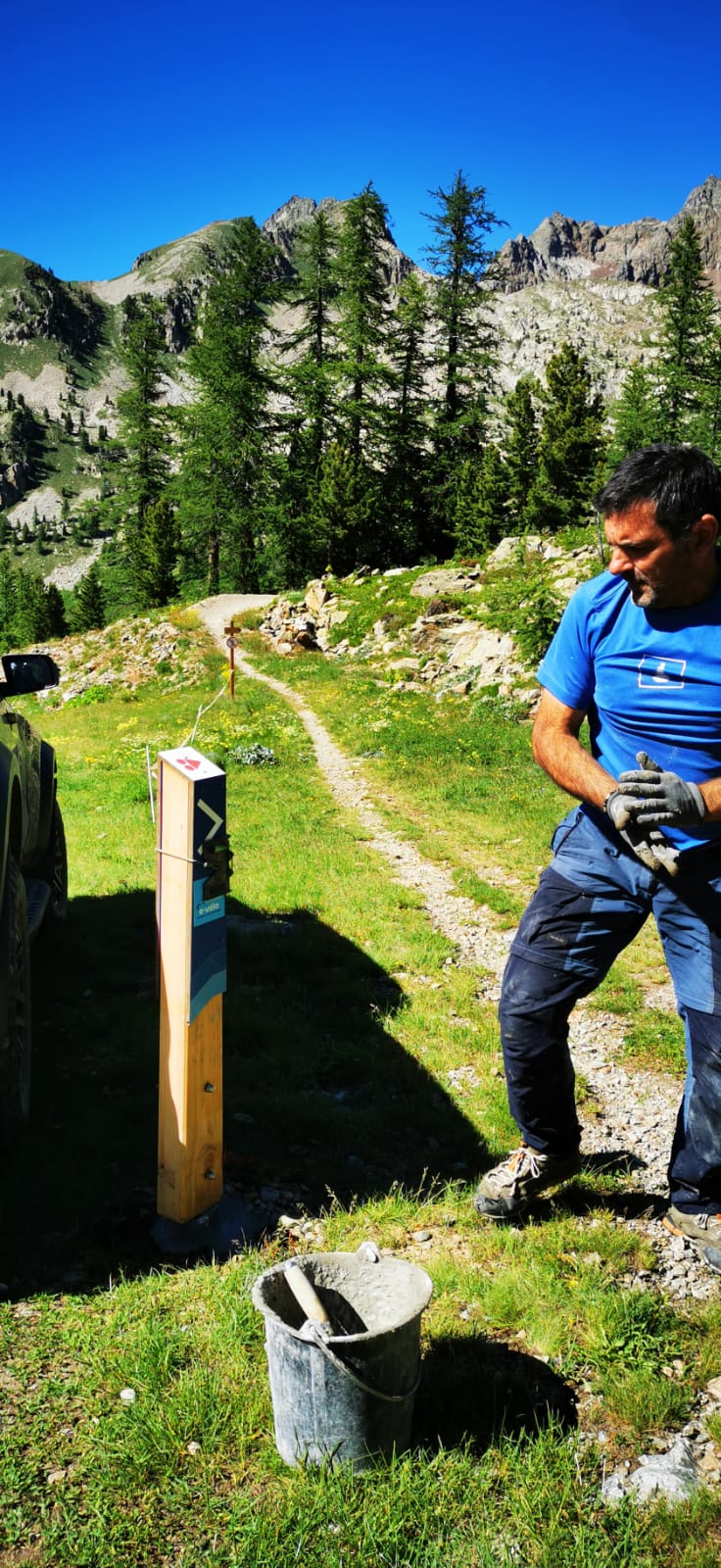 Pose d’une borne de signalisation au bord d’un sentier de montagne.