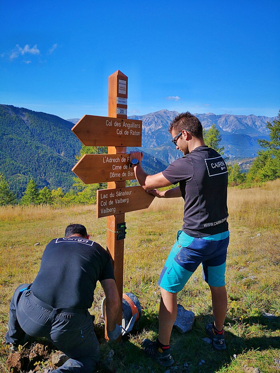 Deux intervenants CAIRN Expe installent un poteau directionnel sur les sentiers de Valberg.