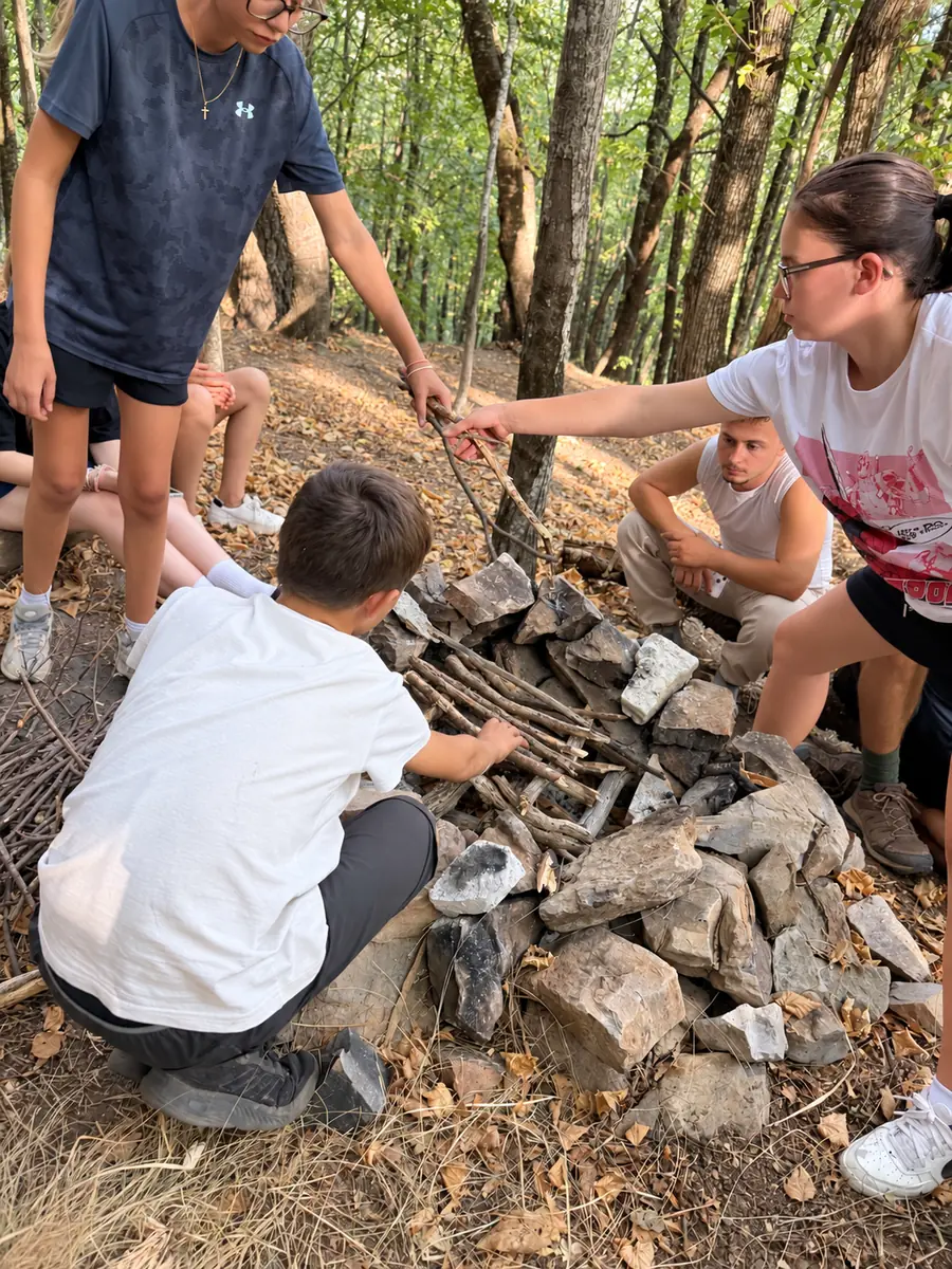 Groupe de participants disposant du bois dans un foyer entouré de pierres en forêt