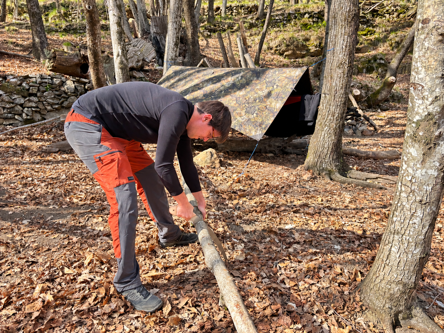 Préparation du bois au campement devant un abri en forêt