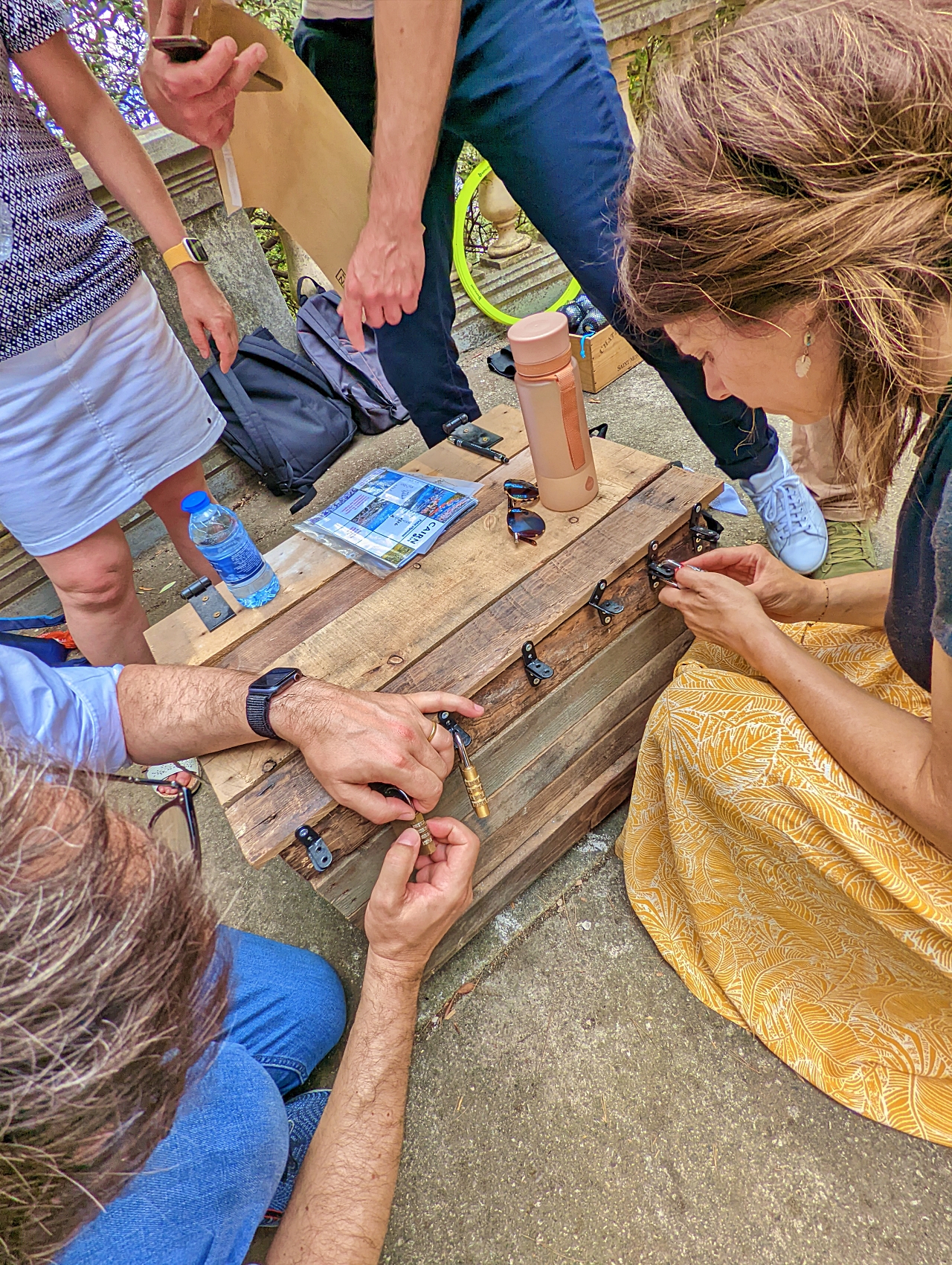 Des participants manipulent les cadenas d’un grand coffre en bois.