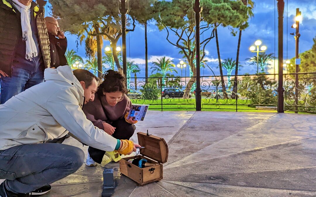 Participants découvrant un petit coffre sous un kiosque à Nice.