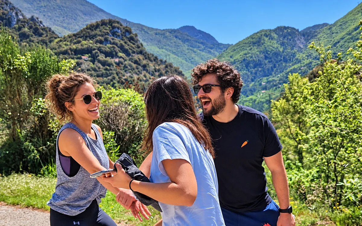 Trois participants échangent en plein air devant des montagnes verdoyantes.