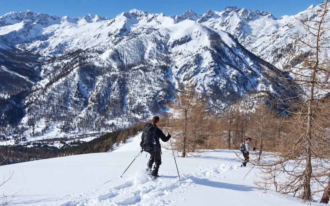 Deux randonneurs en raquettes devant un panorama de sommets enneigés