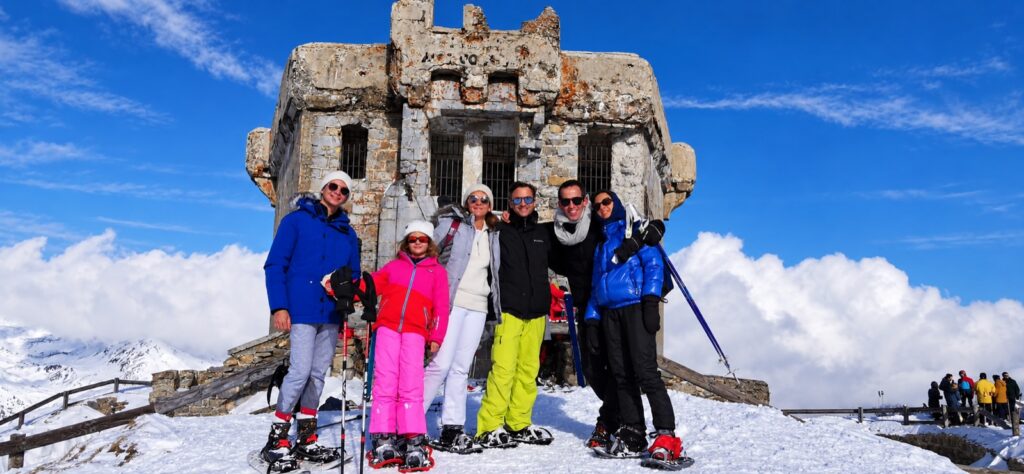 Groupe de randonneurs devant un ancien bâtiment en pierre dans la neige.