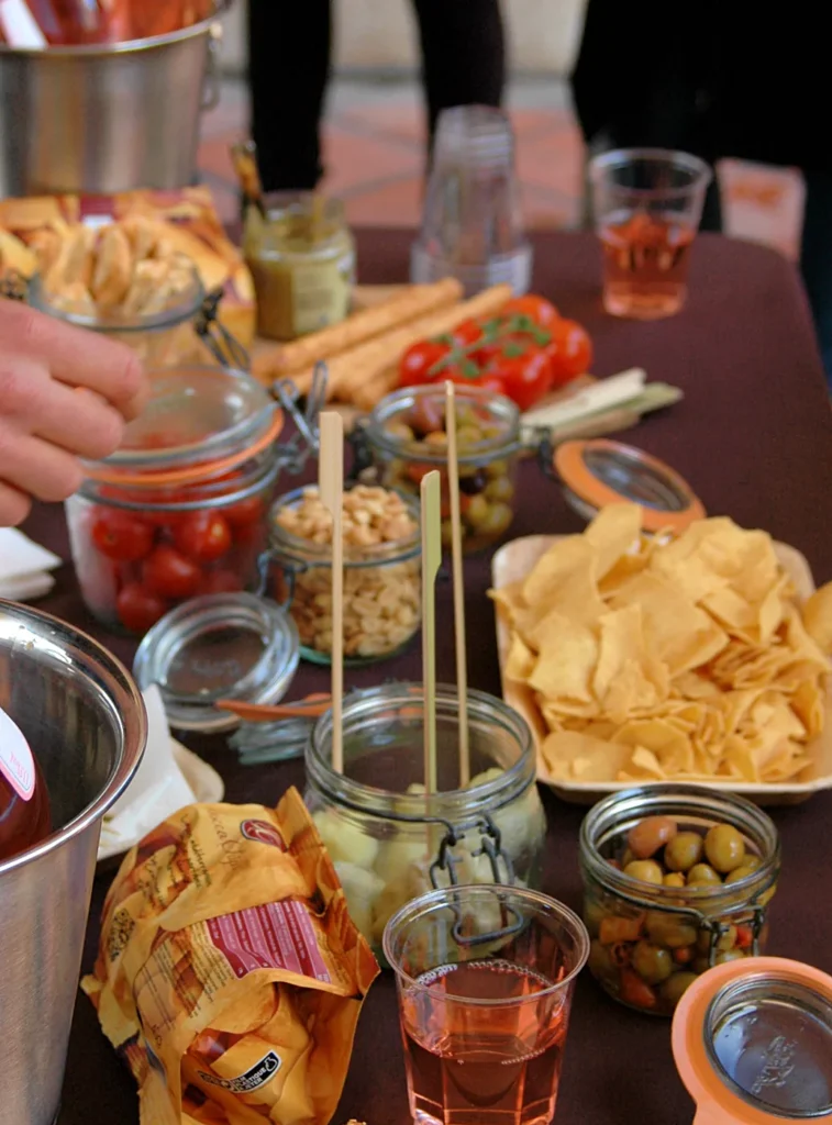Table d’apéritif avec chips, olives, légumes et boissons.