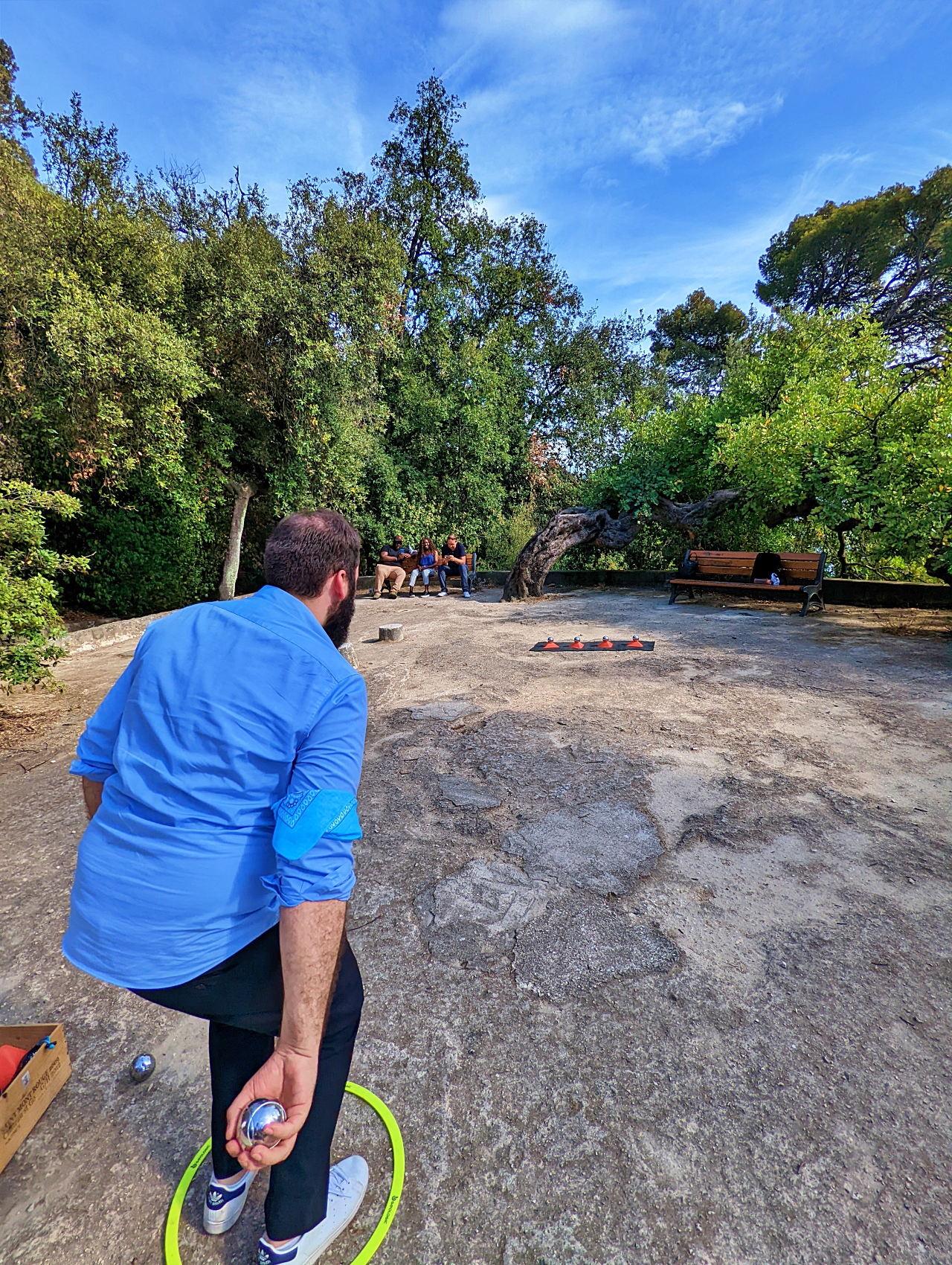Un participant s’apprête à lancer une boule de pétanque en extérieur.