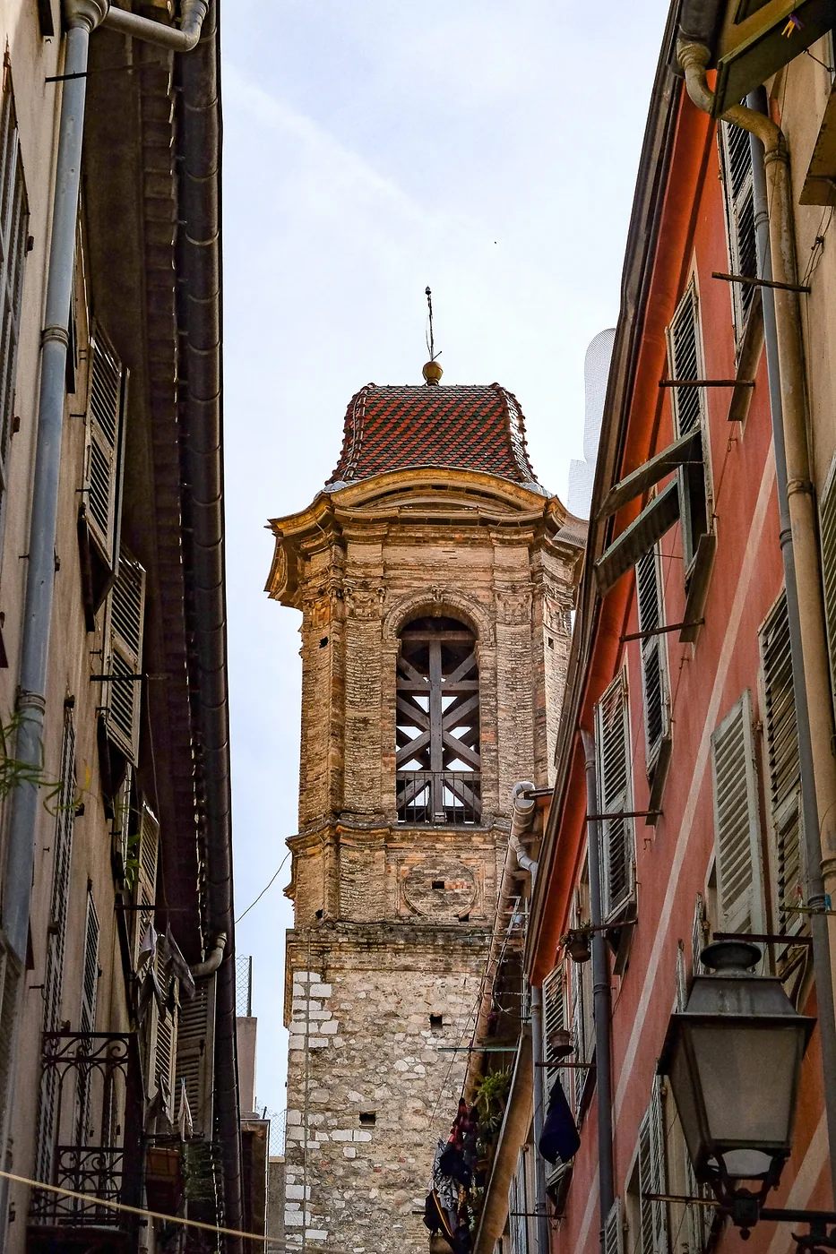Clocher encadré par les façades et les volets d’une ruelle du Vieux-Nice.